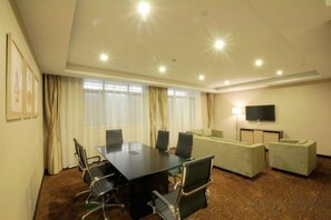Una sala de conferencias con una mesa, sillas, un sofá y un televisor.