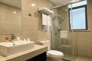A modern bathroom with a sink, toilet, and glass shower enclosure.