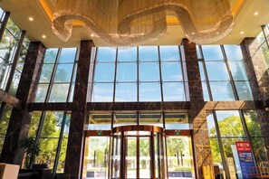 Een hotel lobby met een draaideur, grote ramen en een decoratief plafond.