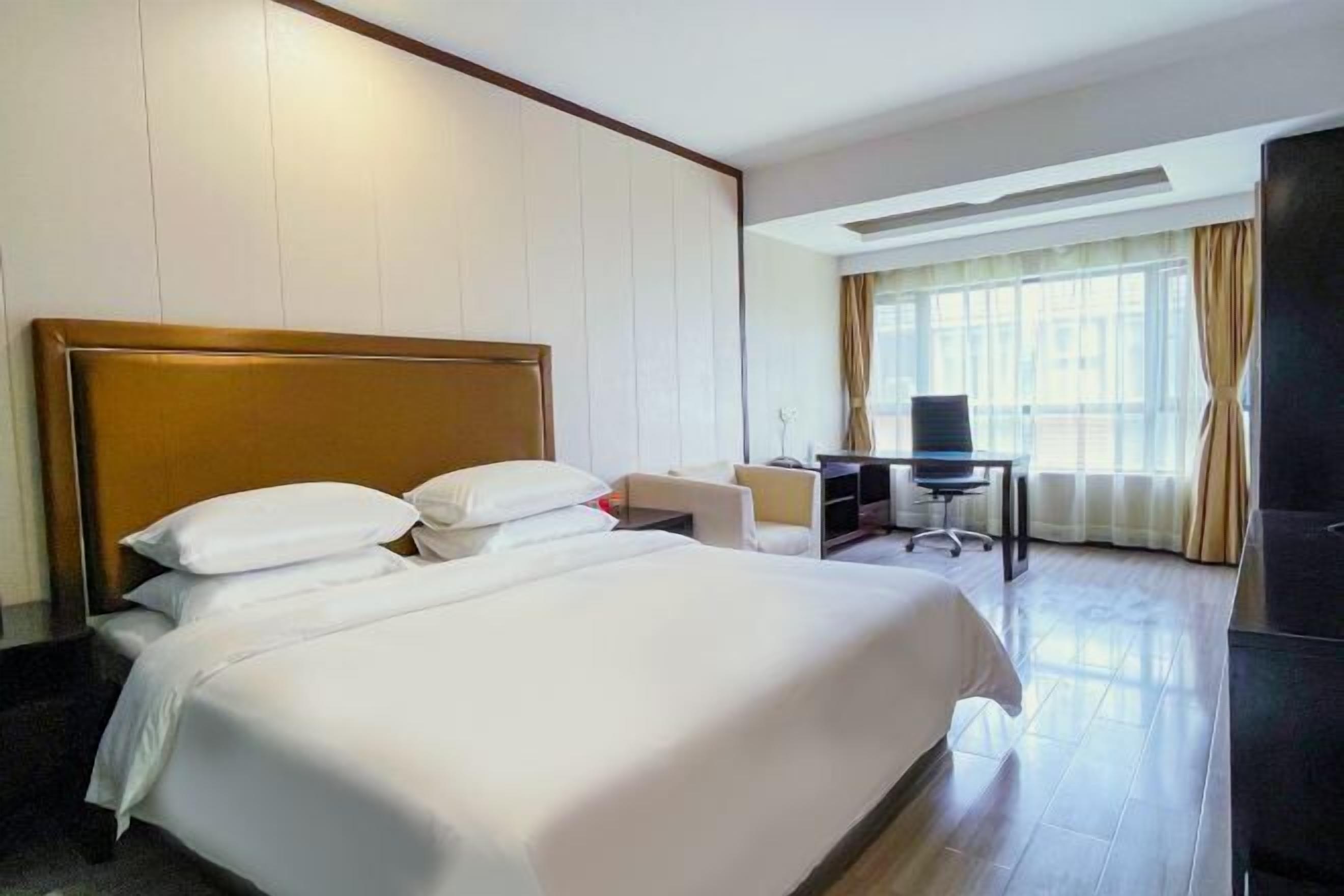Ein Hotelzimmer mit einem großen Bett, einem Schreibtisch und einem Fernseher.