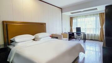 Ein Hotelzimmer mit einem großen Bett, einem Schreibtisch und einem Fernseher.