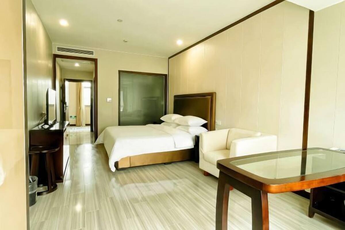 A hotel room with a bed, a sofa, a desk, and a glass table.