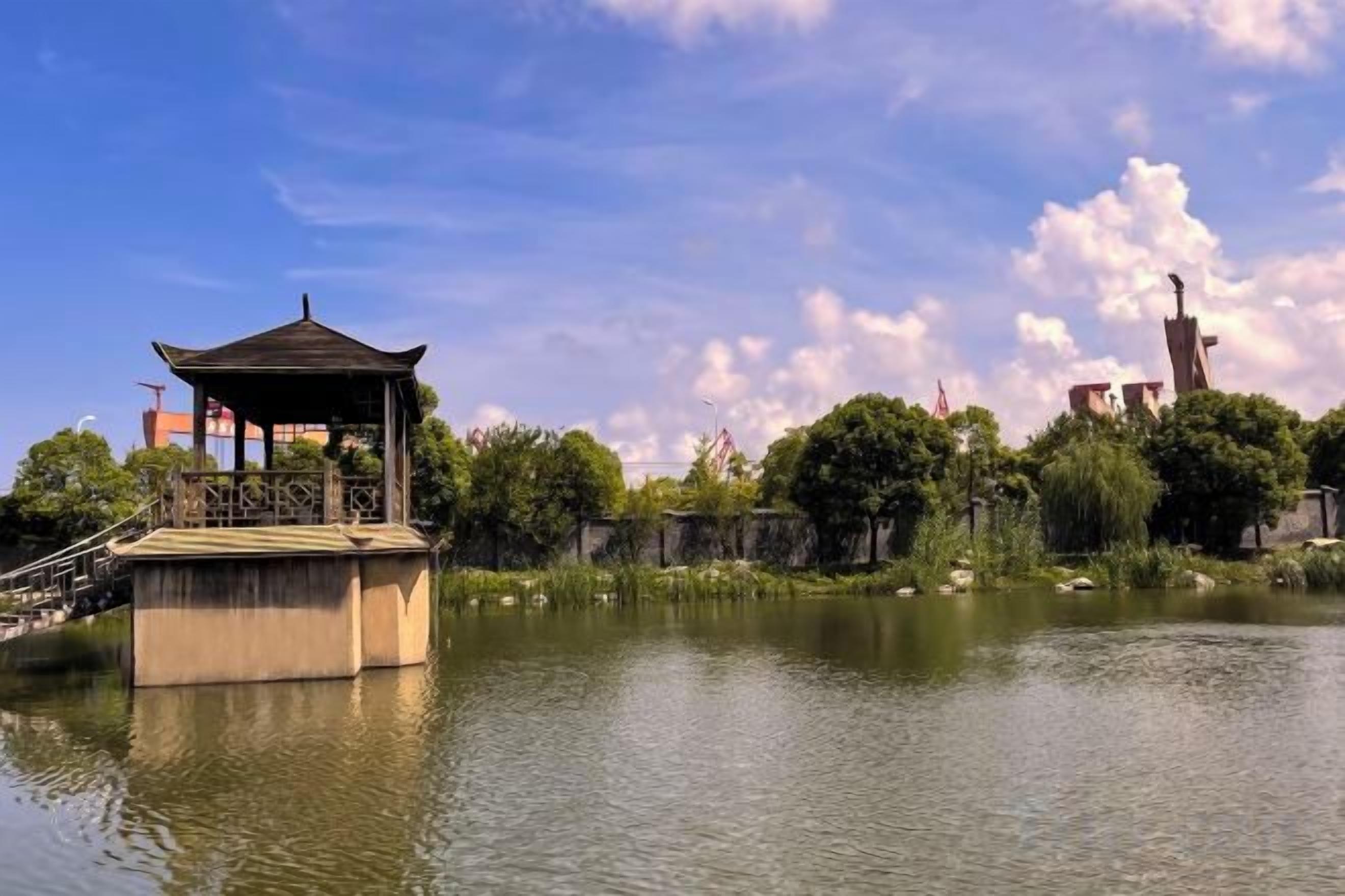Un pavillon construit sur l’eau, avec un ciel dégagé et des bâtiments visibles au loin.