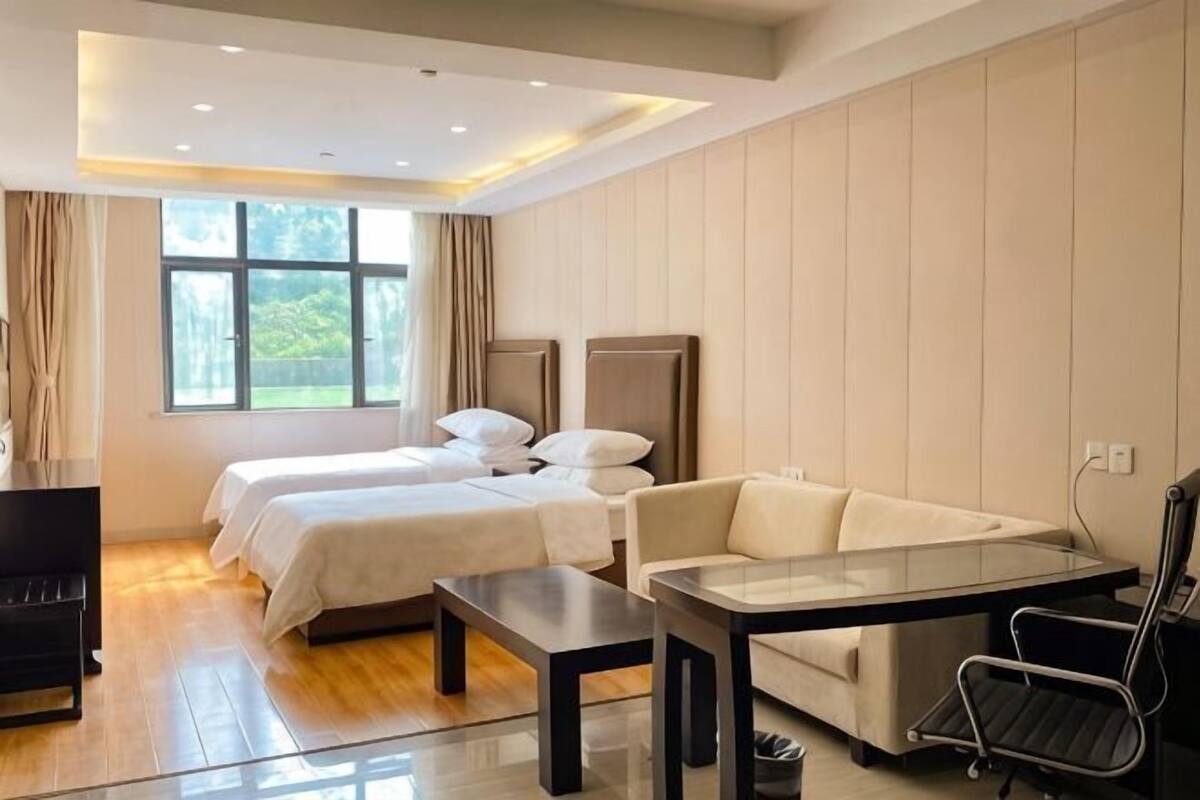 A hotel room with two beds, a sofa, a desk, and a chair.