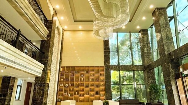 A spacious lobby with a marble floor, a large chandelier, and a wall of decorative items. - Shanghai Changxing International Hotel (Shanghai)