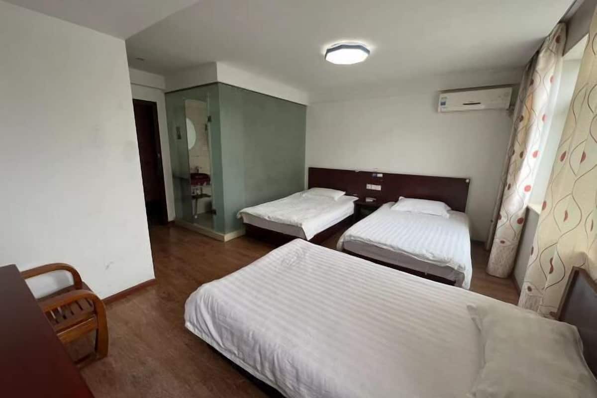 A hotel room with two single beds, a wooden desk, a chair, and a mirror.