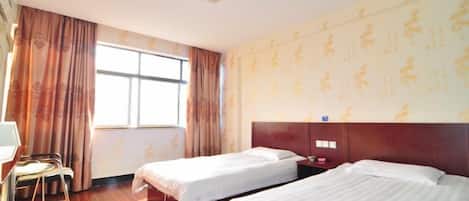 A hotel room with two beds, a desk, and a window with curtains.