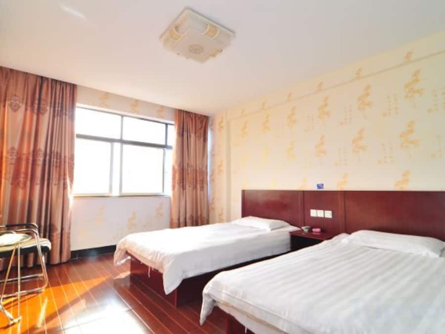 Una habitación de hotel con dos camas, un escritorio y una ventana con cortinas.