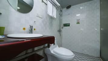 Un baño con inodoro blanco, un lavabo con encimera roja, un espejo y una zona de ducha.