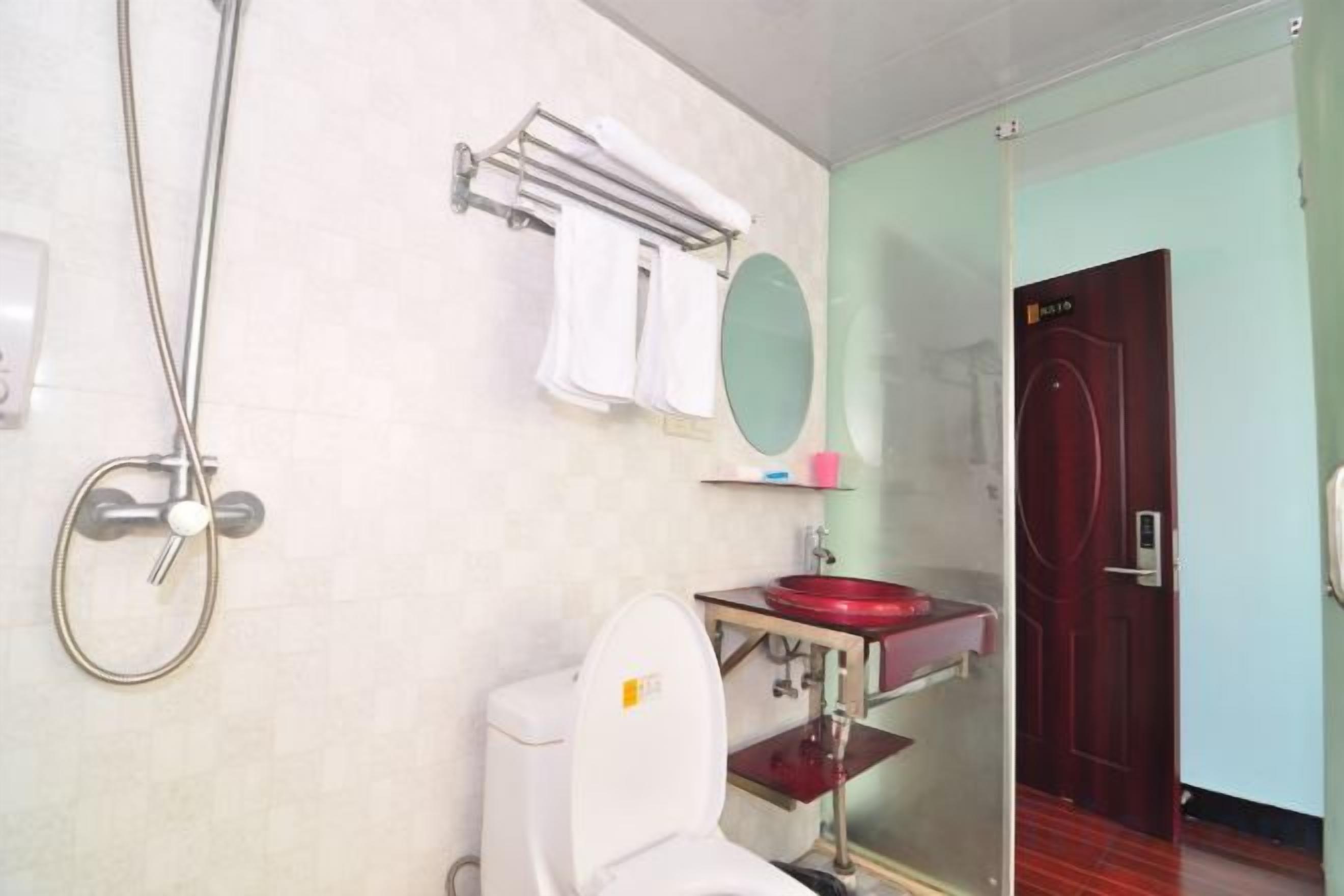 Ein Badezimmer mit Toilette, Waschbecken, Spiegel, Handtuchhalter und Dusche.