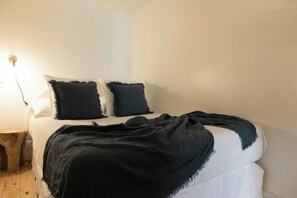 A bed with a white mattress, two pillows, and a dark blanket. - Charming 1BD Flat in Lisbon w/Private Entrance (Lisbon)