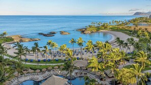 Resort com piscina, praia e palmeiras.