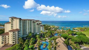 Um resort com um edifício grande, uma piscina e vista para o oceano.
