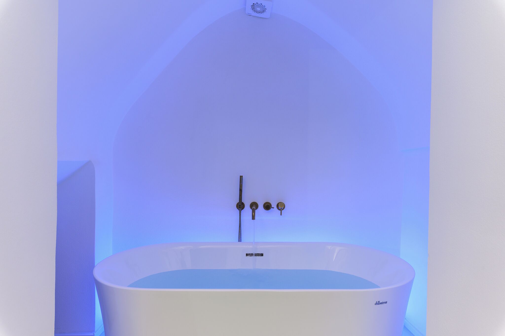 A white bathtub with a control panel, set against a plain wall with a blue light.