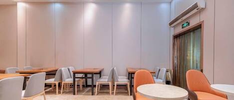 A conference room with tables and chairs, a round table, and a door with an emergency exit sign.
