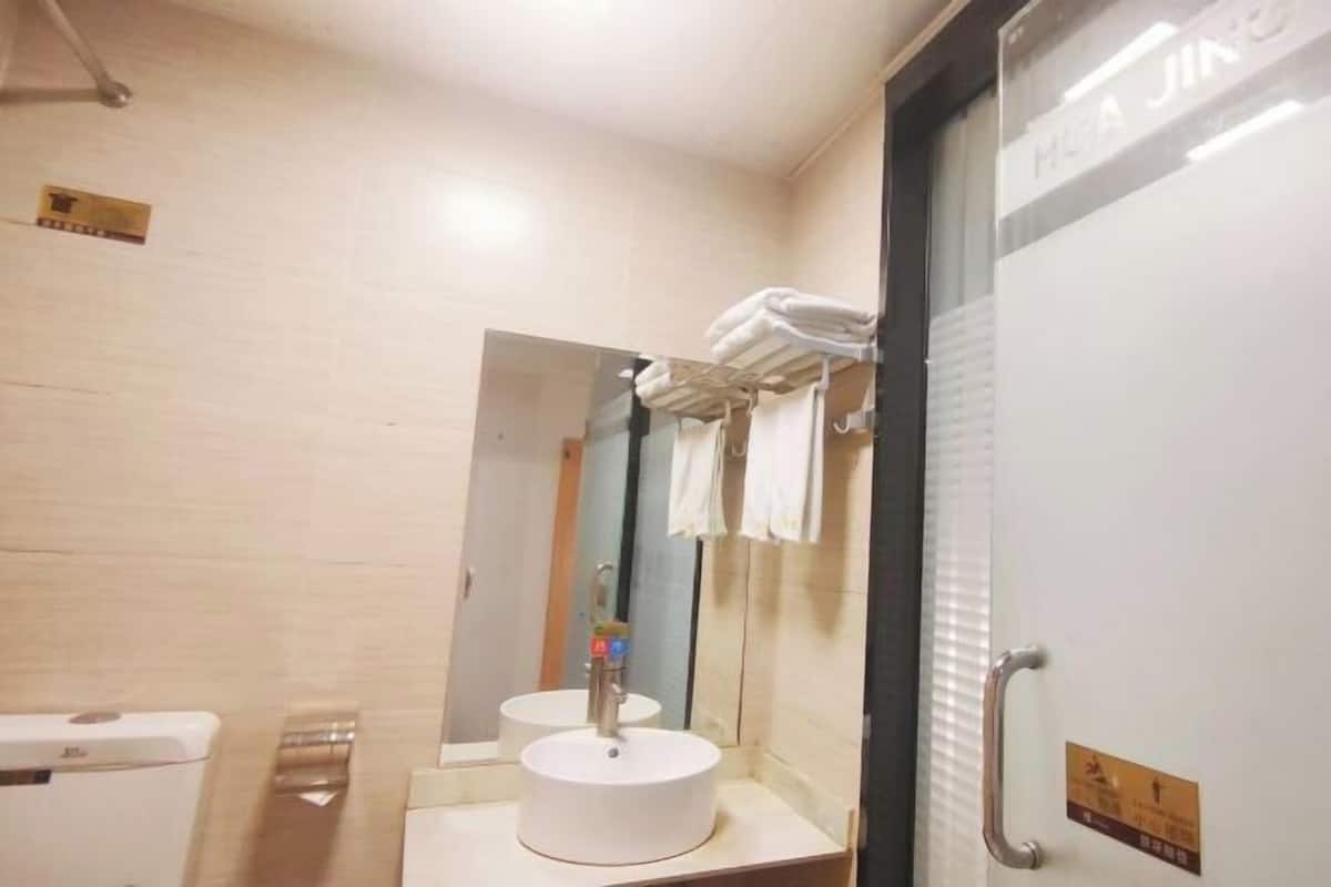 A bathroom with a sink, mirror, towel rack, and a door with a sign.