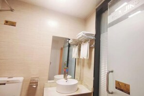 A bathroom with a sink, mirror, towel rack, and a door with a sign. - Huajing Hotel(Yulin Miaoyuan) (Yulin)
