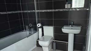 A modern bathroom with a bathtub, toilet, and sink.