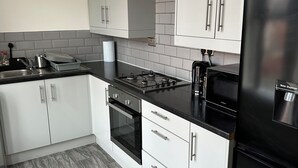 A modern kitchen with white cabinets, a black refrigerator, a stove, and a microwave.