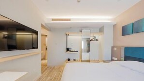 Une chambre d’hôtel avec un lit, un téléviseur fixé au mur, un miroir et une petite table.