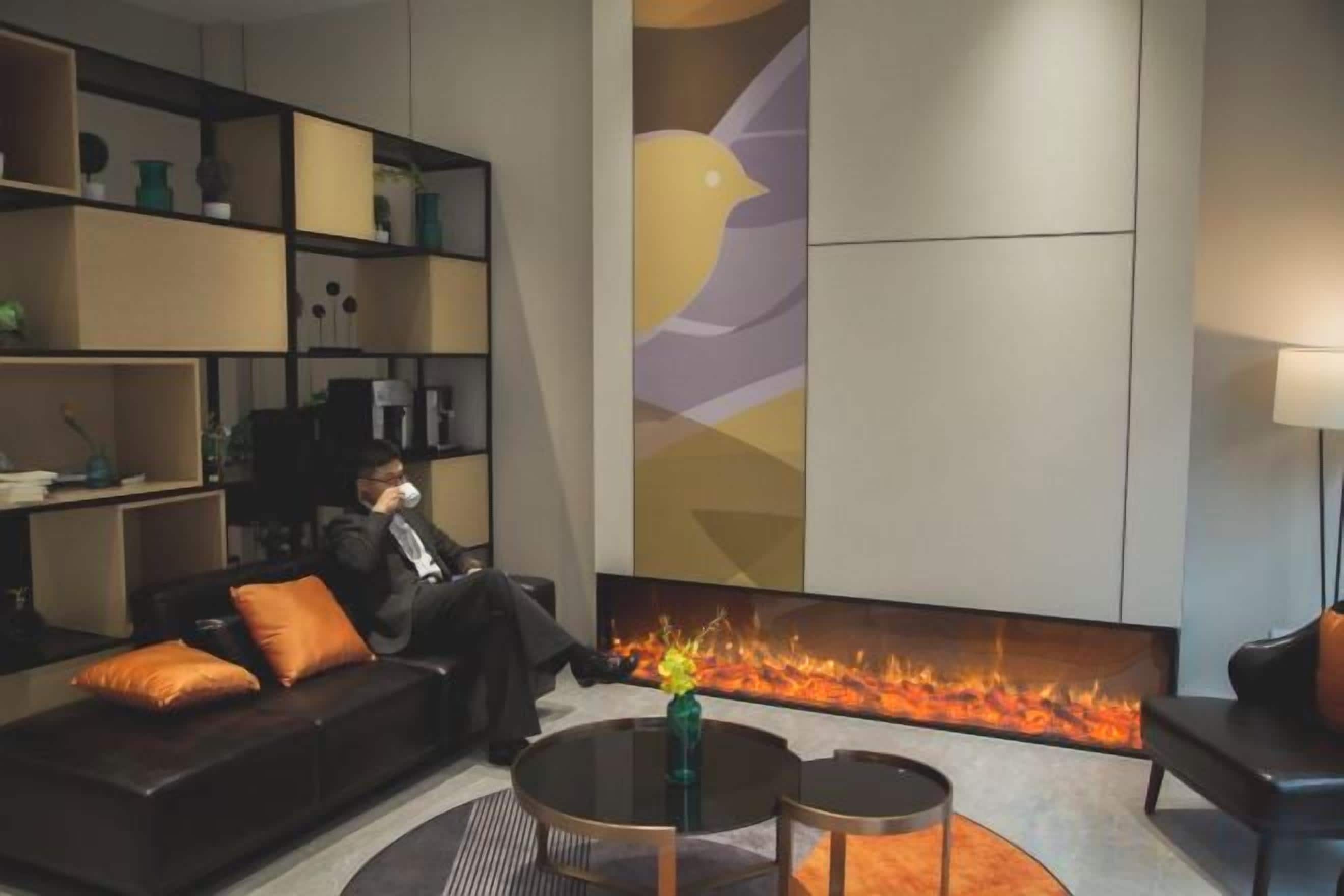 A modern living room with a fireplace, a sofa, a coffee table, and a bookshelf.