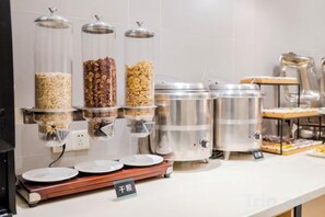 Montaje tipo bufé con múltiples dispensadores de comida y una olla grande, probablemente para sopas o guisos.