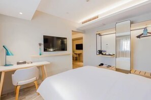 A hotel room with a bed, a desk, a chair, a TV, and a mirror. - Xin Huifeng Business Hotel (Lishui Station Wandi Plaza) (Lishui)