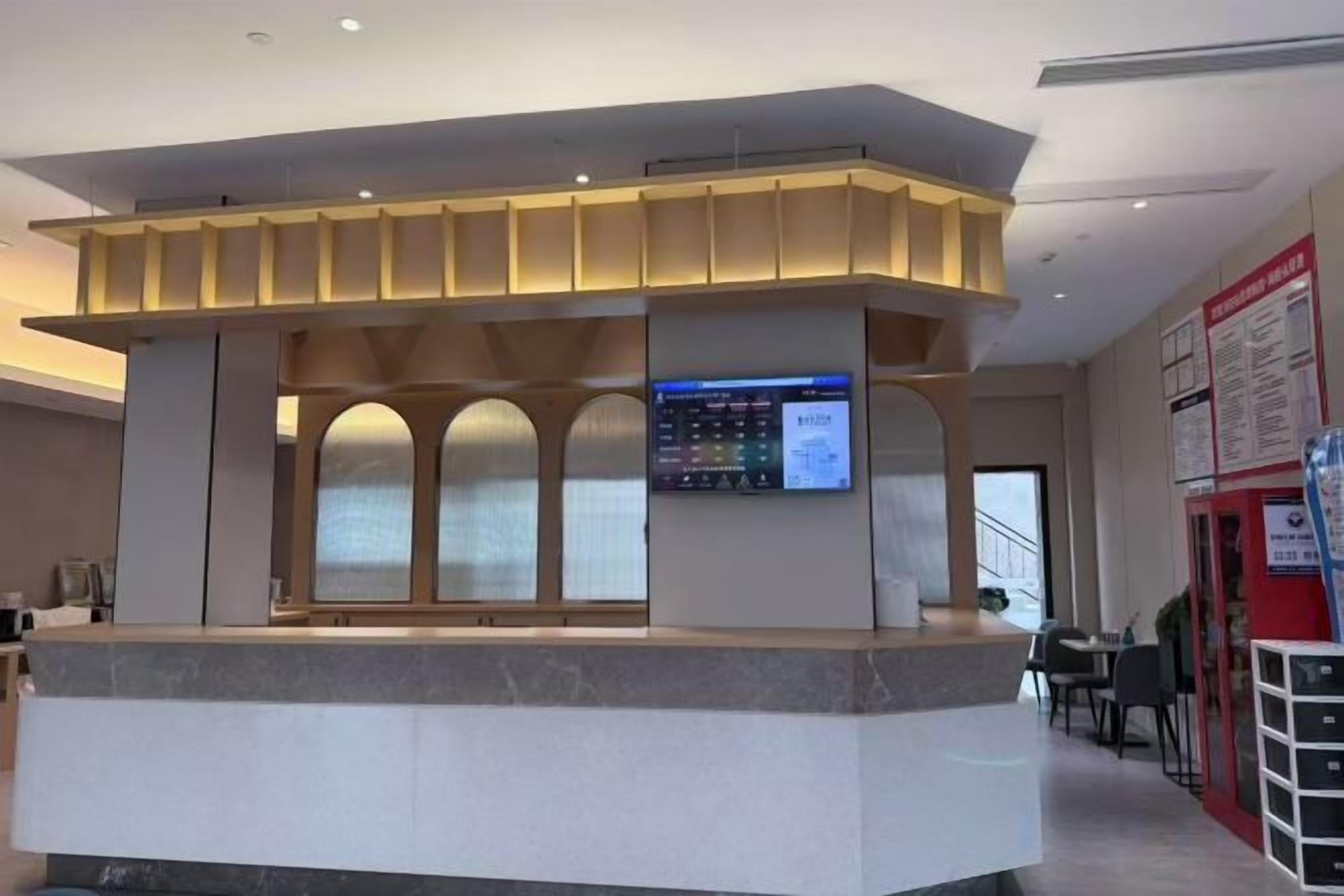 A reception desk with a digital screen, a counter, and a seating area with tables and chairs.