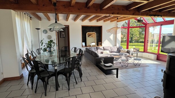 A spacious living area with a dining table and chairs, a sofa, and a TV. - Grande Maison à la Campagne aux Portes du Morvan (Fours)