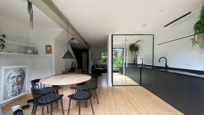 Une cuisine moderne avec une table à manger ronde, des chaises noires et un plancher en bois.