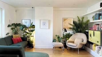 A modern living room with a sofa, armchair, and a bookshelf.