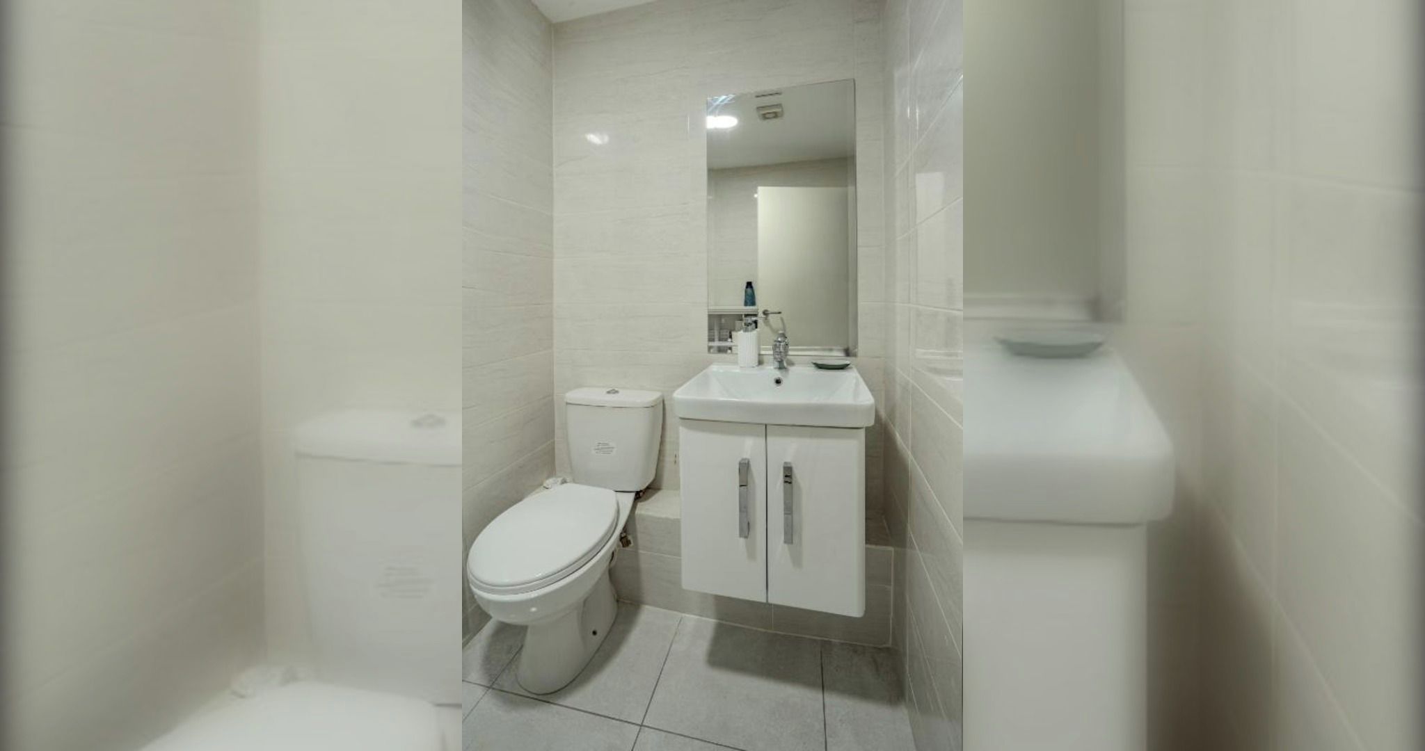 A bathroom with a toilet, sink, and mirror.