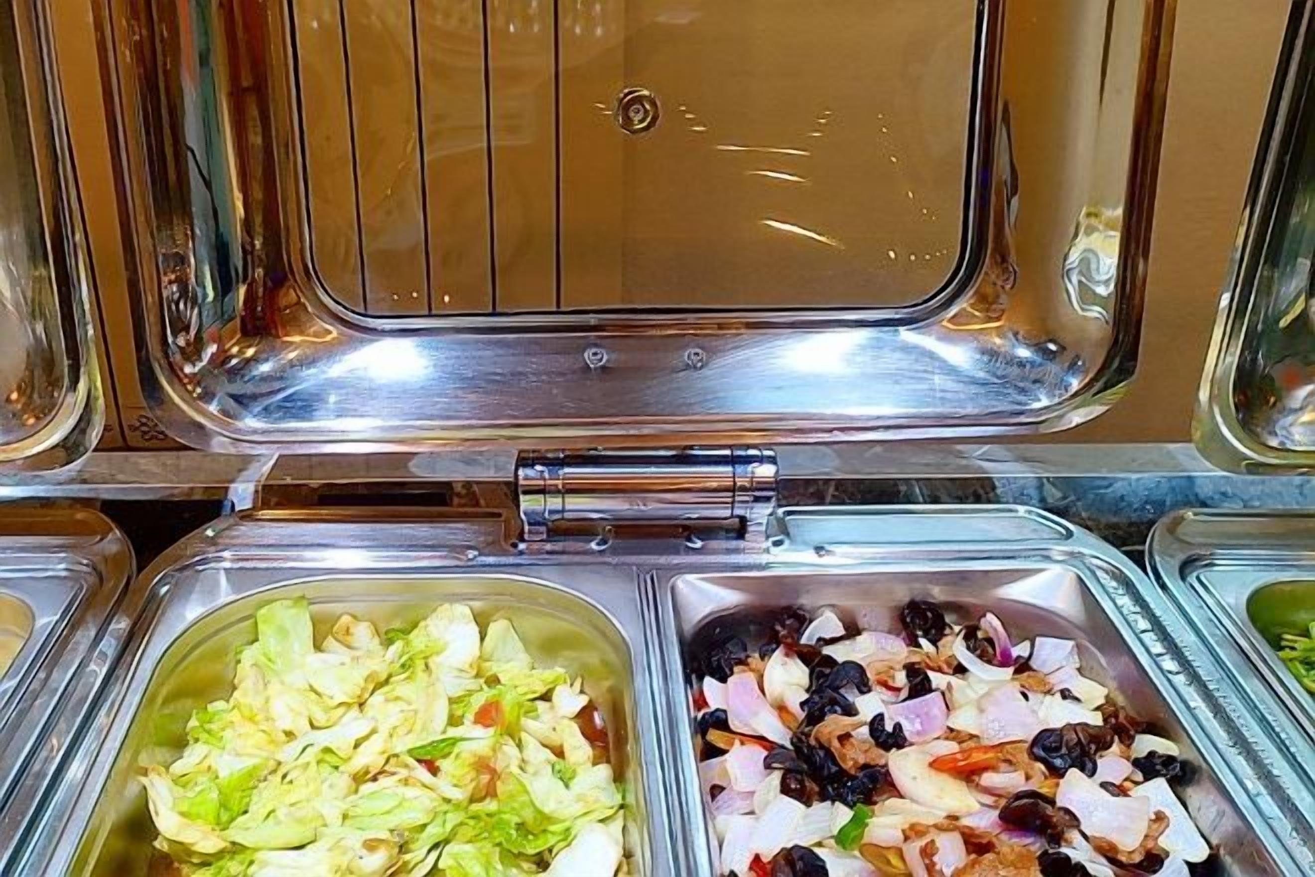 A buffet with various food options in metal containers.