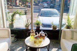 Una habitación con vista a la calle, una mesa con una jofaina y tetera, y dos sillas.