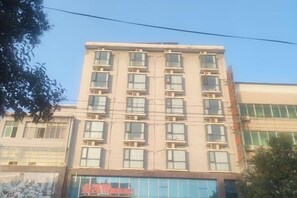 Un edificio de varios pisos con fachada plana, múltiples ventanas y un escaparate visible en la planta baja.