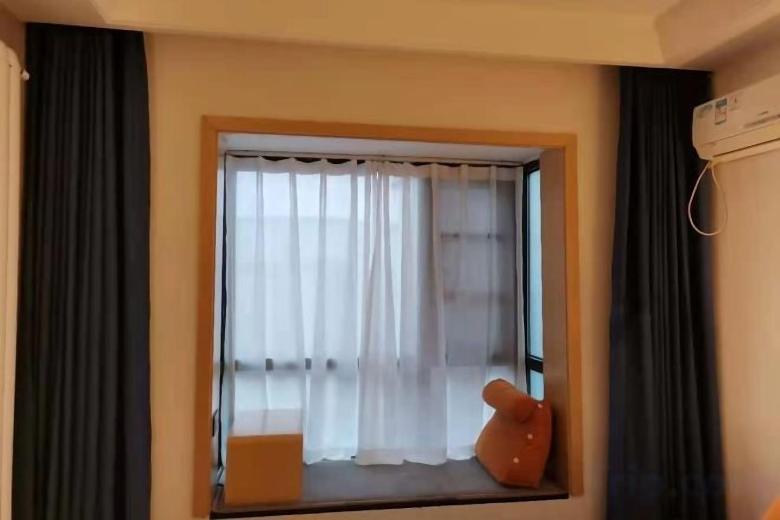 A room with a window, curtains, a small table, and a chair.