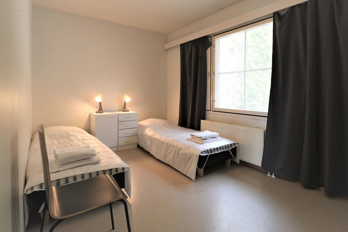 A small, clean room with a bed, a desk, and a window.