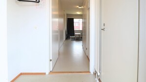 A narrow hallway with white walls and doors, leading to a room with a window and a table. - Forenom Serviced Apartments Porvoo (Porvoo)