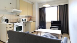 A compact kitchen with basic appliances, a dining area with a table and chairs, and a sofa. - Forenom Serviced Apartments Porvoo (Porvoo)