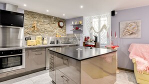 A modern kitchen with stainless steel appliances, a stone accent wall, and a central island.