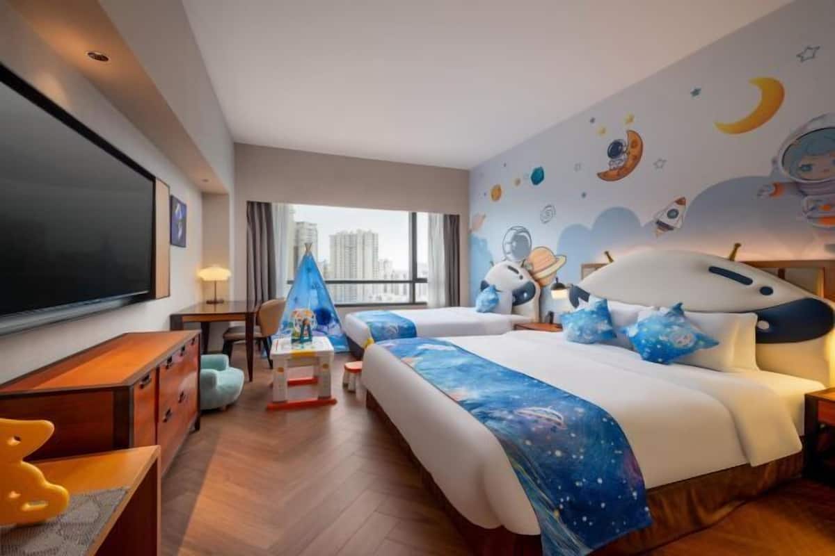 Ein Hotelzimmer mit einem großen Bett, einem Schreibtisch, einem Fernseher und Blick auf die Stadt.