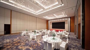 A conference room with round tables, white chairs, and a large screen. - Grand Madison Kunshan Huaqiao (Kunshan)