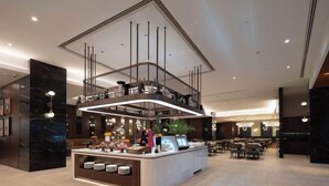 A modern hotel lobby with a central reception desk, seating area, and a mezzanine level with a railing. - Grand Madison Kunshan Huaqiao (Kunshan)