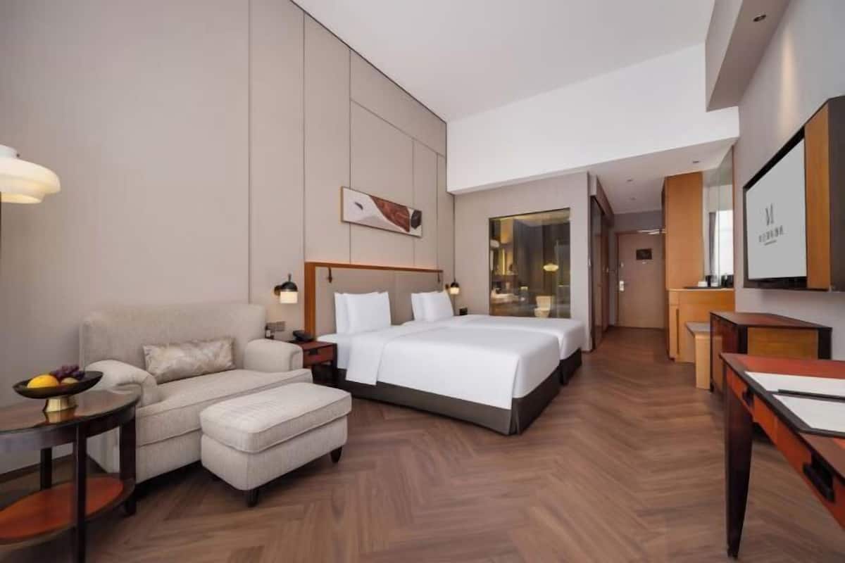 Ein Hotelzimmer mit einem großen Bett, einer Schlafcouch, einem Schreibtisch und einem Spiegel.