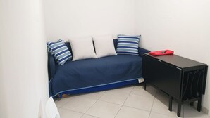 Ein kleiner, kompakter Raum mit einem blauen Sofa, einem schwarzen Schreibtisch und einem roten Gegenstand auf dem Schreibtisch.