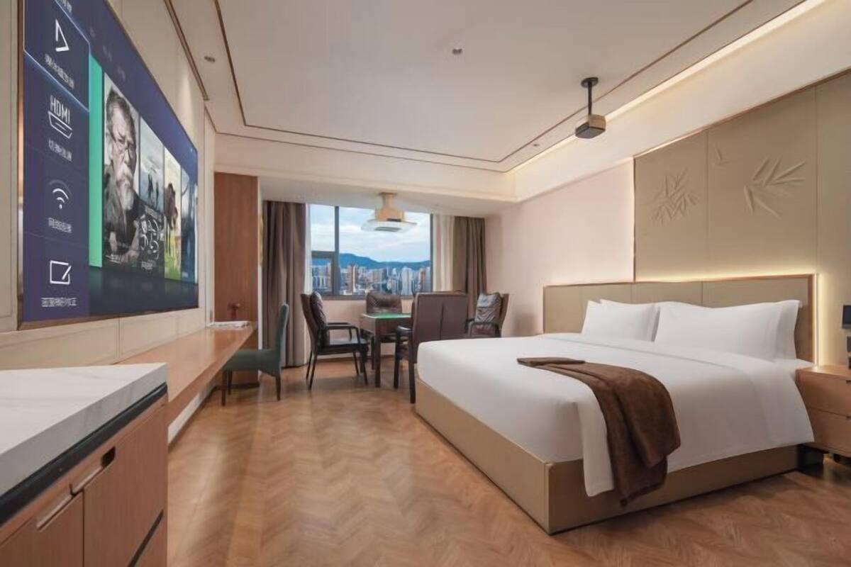 Een hotelkamer met een groot bed, een bureau en uitzicht op de stad.