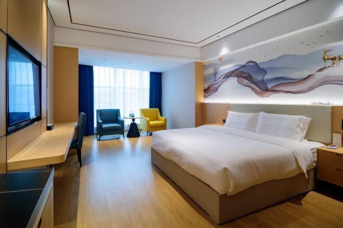 Een hotelkamer met een groot bed, een televisie, een bureau en een stoel.