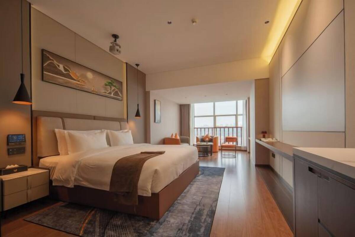 Een moderne hotelkamer met een groot bed, een bureau, een stoel en uitzicht op de stad.
