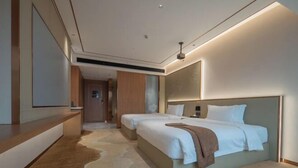 Une chambre d’hôtel moderne avec un grand lit, une table de chevet, un miroir et un sol recouvert de moquette.