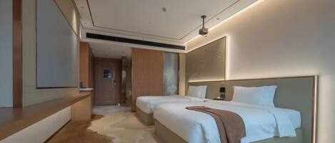 A modern hotel room with a large bed, a bedside table, a mirror, and a carpeted floor.